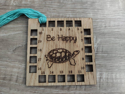 Square shape thread holder, with tortoise and "be happy" engraved in the middle. 20 holes for thread. 