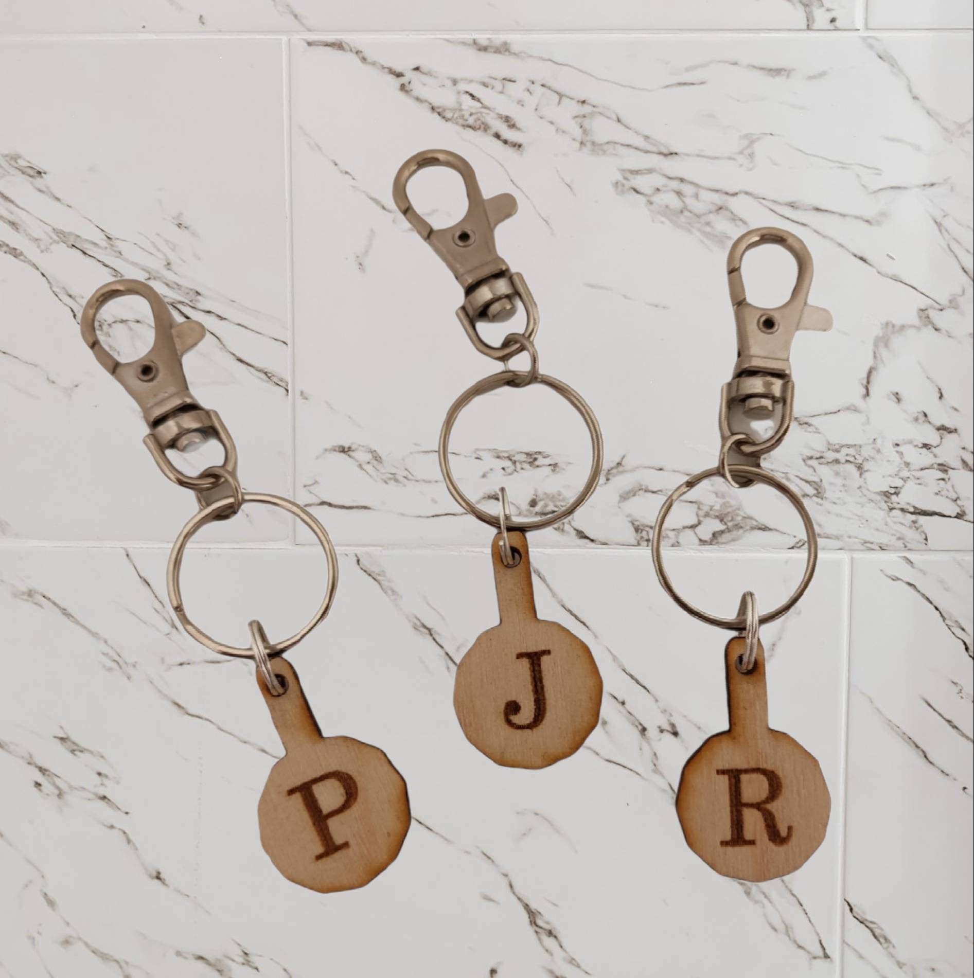 Personalised trolley keyring with a letter initial or Christmas design, same shape and thickness as a £1 coin, attached to a split ring and clip.