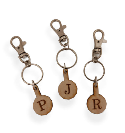 Personalised trolley keyring with a letter initial or Christmas design, same shape and thickness as a £1 coin, attached to a split ring and clip.
