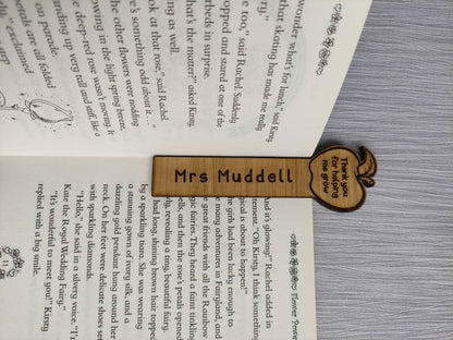 Wooden bookmark with custom name engraving, featuring a flower or apple design at the top.