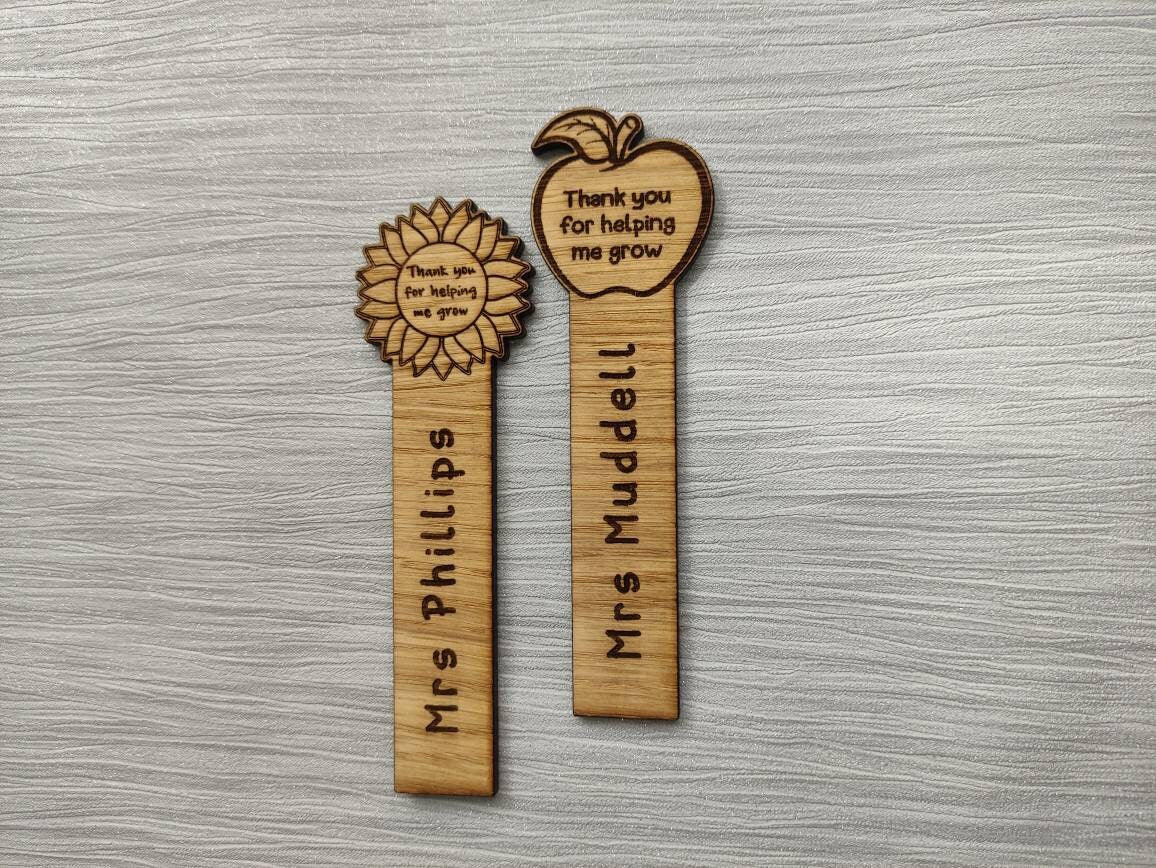 Wooden bookmark with custom name engraving, featuring a flower or apple design at the top.