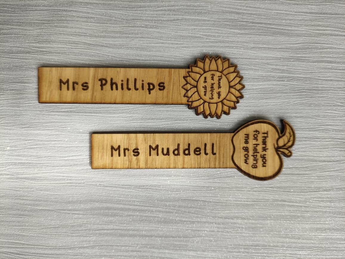 Wooden bookmark with custom name engraving, featuring a flower or apple design at the top.
