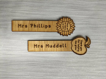 Wooden bookmark with custom name engraving, featuring a flower or apple design at the top.