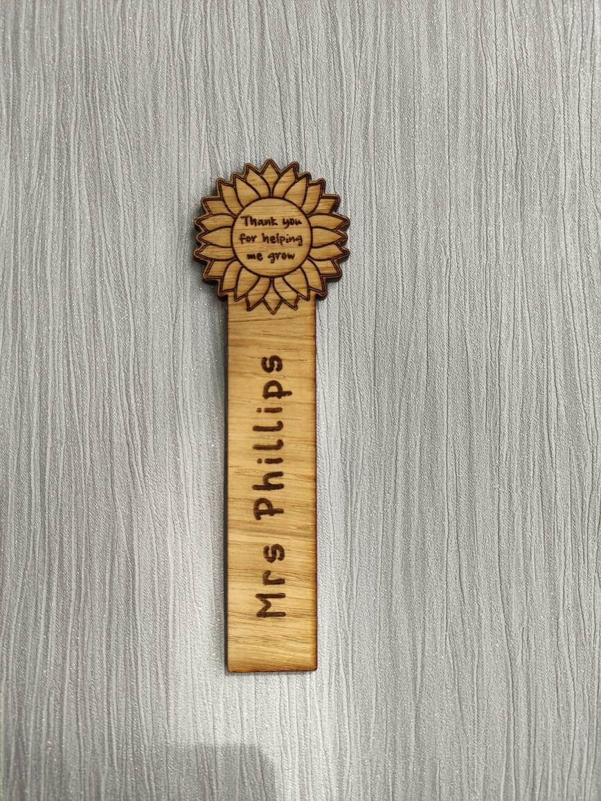 Wooden bookmark with custom name engraving, featuring a flower design at the top.