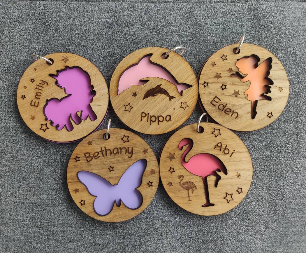 Circular wooden keyring with a unicorn cut-out, backed with colourful acrylic and personalised with an engraved name.
