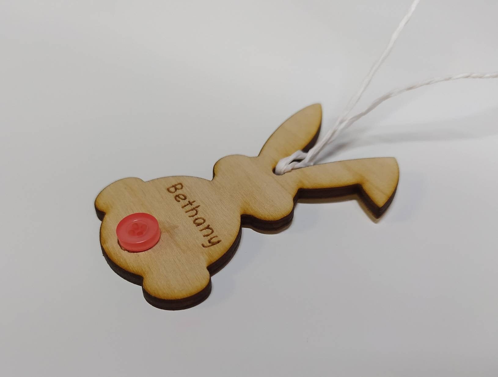 Easter bunny-shaped hanging decoration, engraved with a personalised name and featuring a coloured button as the tail.