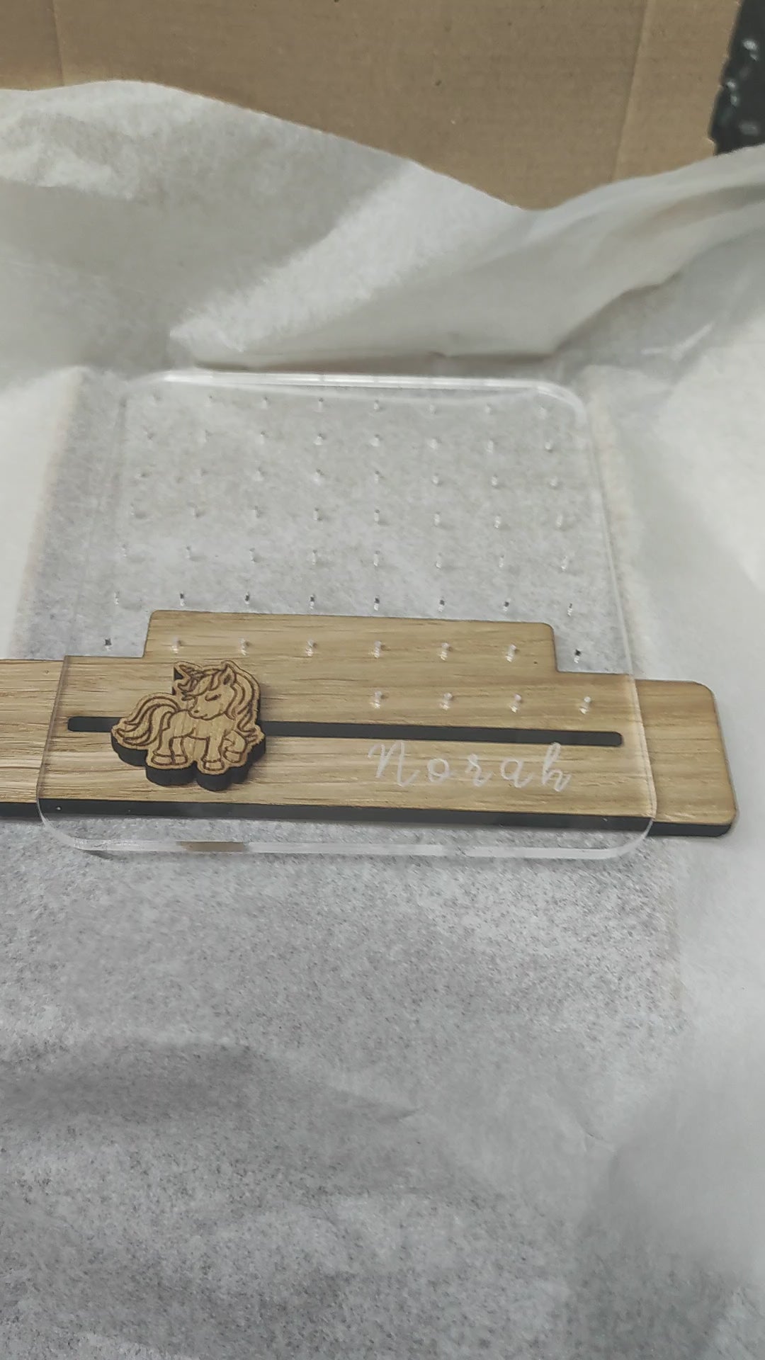 Clear acrylic earring holder with a custom engraved name across the bottom and a detailed unicorn design. Holds multiple pairs of earrings, combining functionality with a cute, stylish touch. Made from 100% recycled acrylic.
